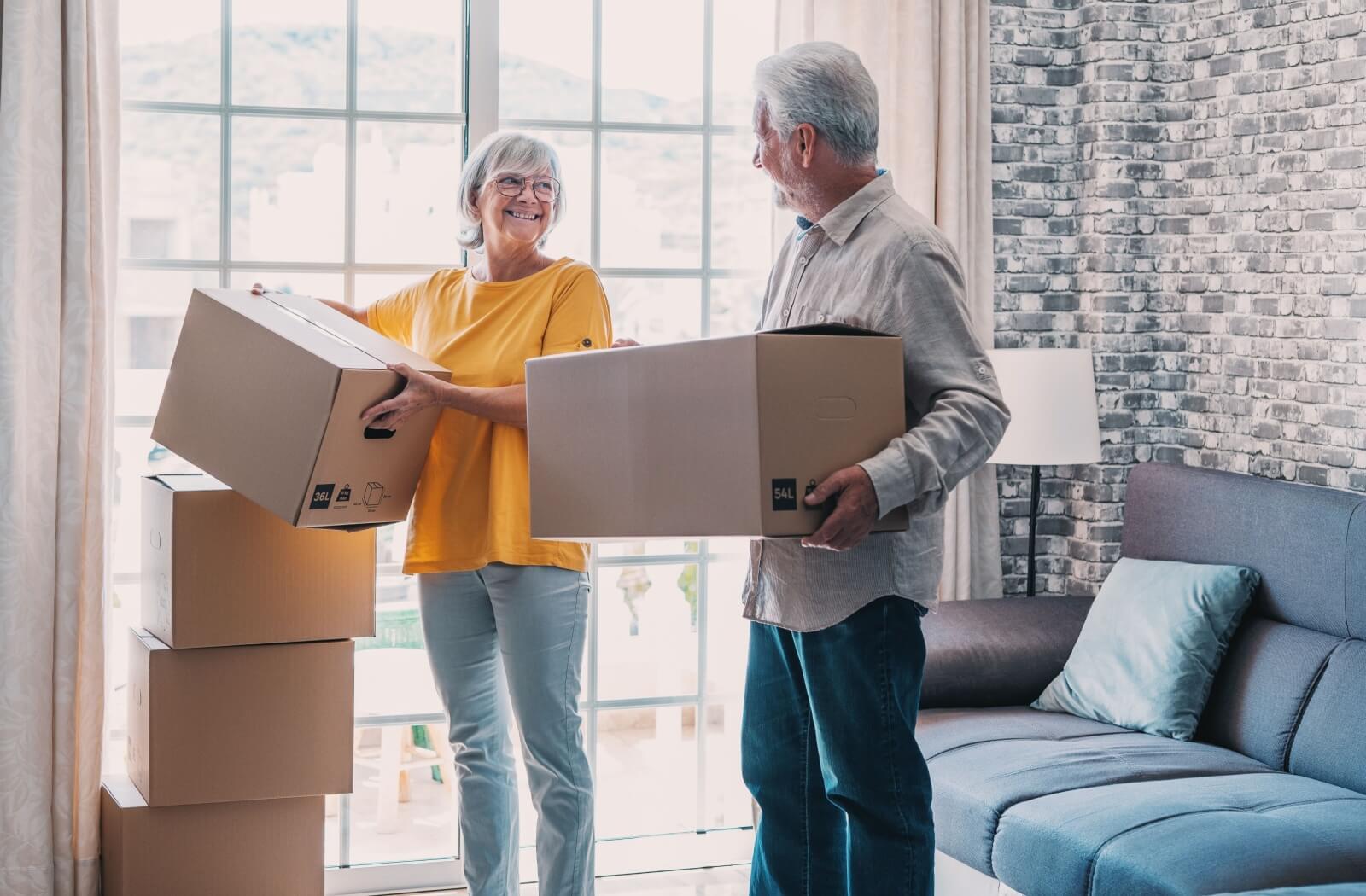 Two seniors move boxes as they start to move into a retirement community.